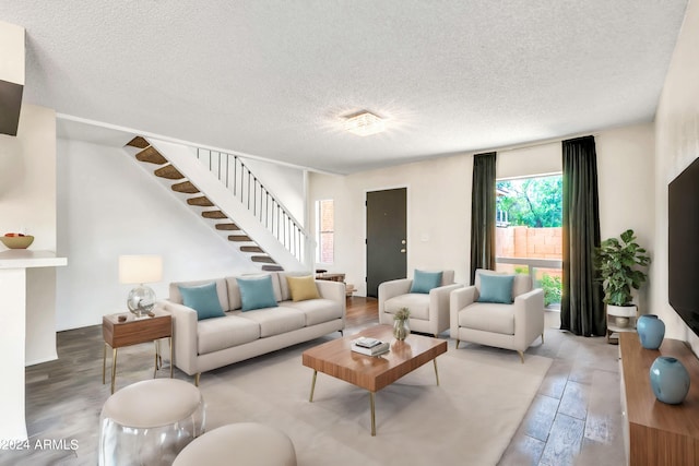 living room featuring a textured ceiling, stairs, and wood finished floors