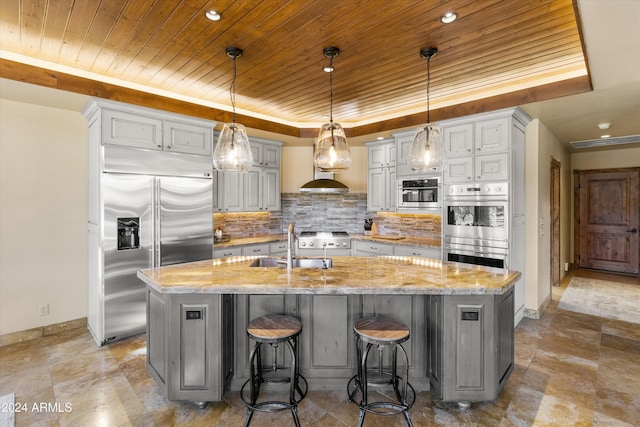 kitchen featuring light stone countertops, appliances with stainless steel finishes, and a center island with sink