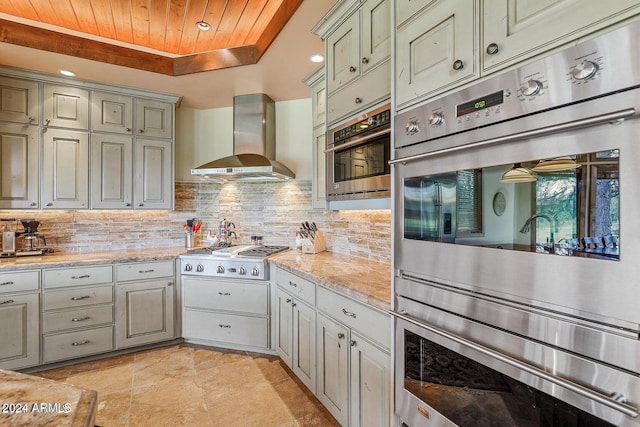 kitchen with backsplash, wood ceiling, wall chimney range hood, and appliances with stainless steel finishes