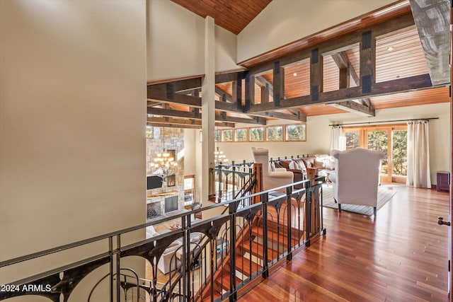 stairs featuring a notable chandelier, lofted ceiling with beams, wood-type flooring, and wood ceiling