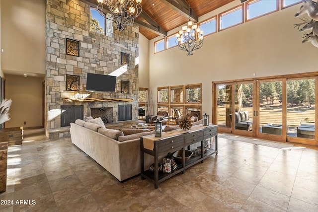 living room featuring a stone fireplace, a chandelier, a towering ceiling, and wood ceiling