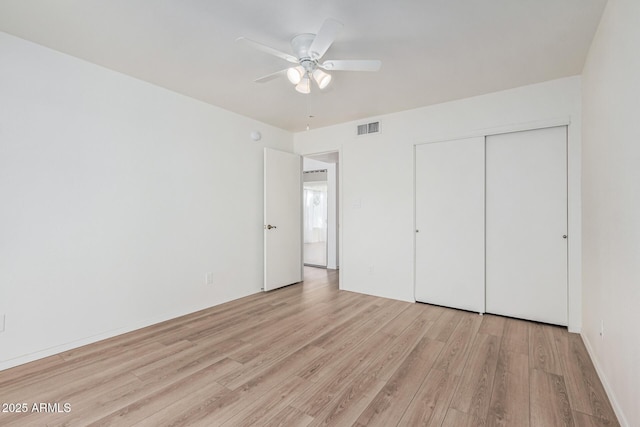 unfurnished bedroom featuring ceiling fan, a closet, and light wood-type flooring