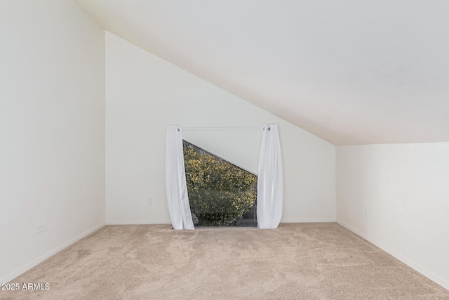 bonus room with light colored carpet and vaulted ceiling