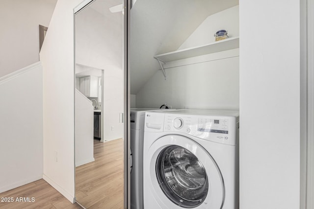 clothes washing area featuring light wood-type flooring and washer / dryer