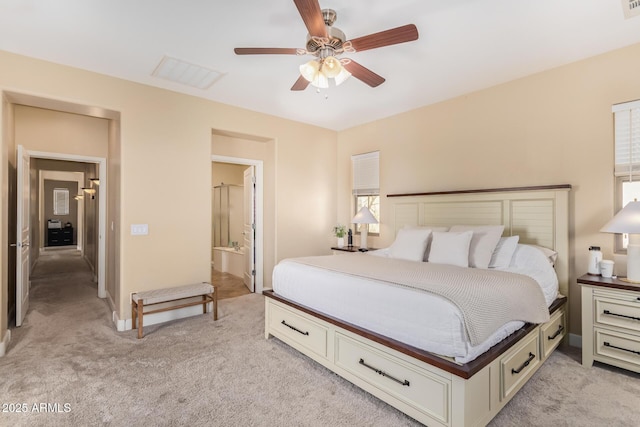 bedroom featuring ceiling fan, visible vents, light carpet, and ensuite bath