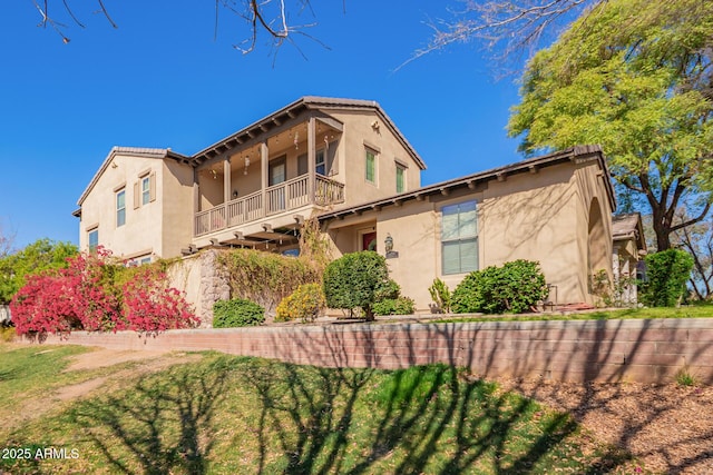 view of home's exterior with stucco siding, a balcony, and a yard