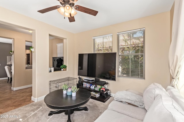 living area with ceiling fan and baseboards