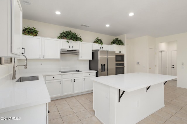 kitchen with sink, a breakfast bar area, stainless steel appliances, a center island, and white cabinets