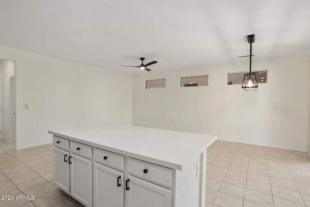 kitchen with hanging light fixtures, light tile patterned flooring, ceiling fan, and a kitchen island