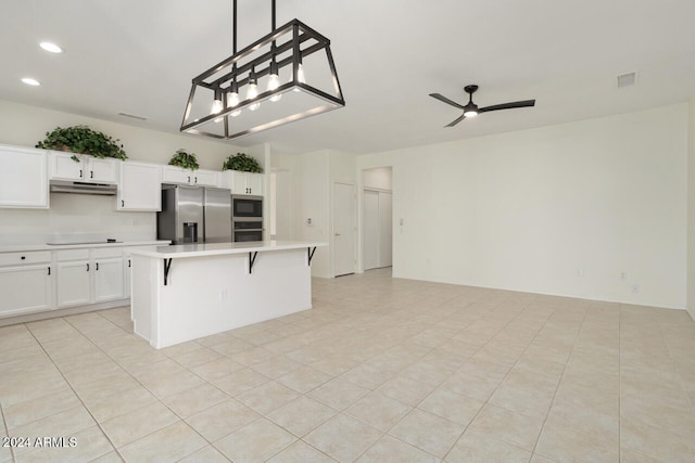 kitchen featuring hanging light fixtures, appliances with stainless steel finishes, a kitchen island, ceiling fan, and white cabinets