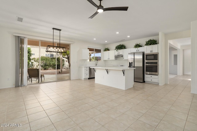 kitchen featuring a kitchen island, appliances with stainless steel finishes, a kitchen breakfast bar, hanging light fixtures, and light tile patterned floors