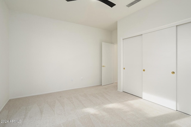 unfurnished bedroom with light carpet, ceiling fan, and a closet