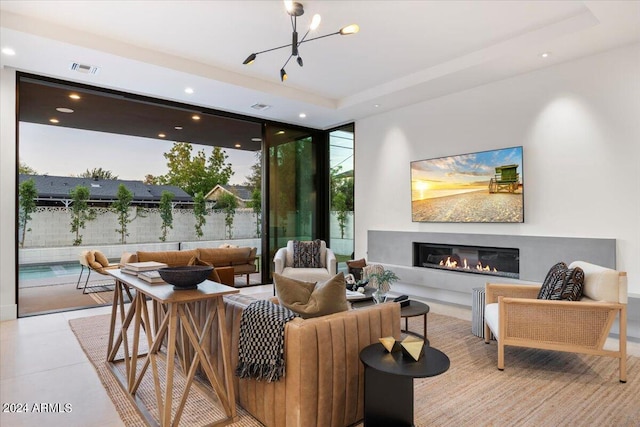 living room featuring a wall of windows, a notable chandelier, light tile floors, and a tray ceiling