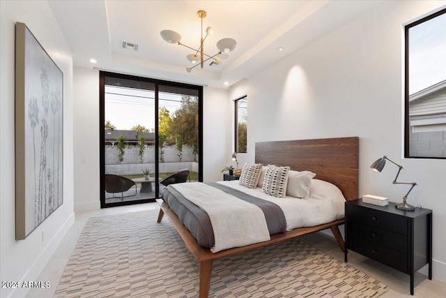 bedroom with an inviting chandelier, access to outside, and a raised ceiling