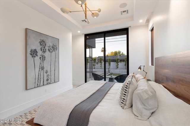 bedroom featuring a notable chandelier, access to outside, and a raised ceiling