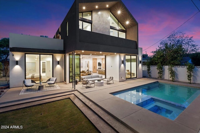 back house at dusk with an outdoor hangout area, a patio, and a pool with hot tub