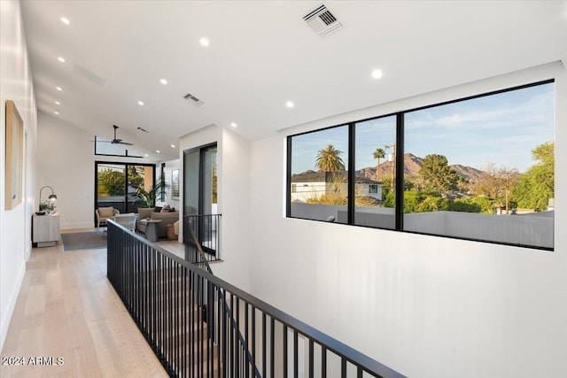 corridor featuring a wealth of natural light, lofted ceiling, and hardwood / wood-style flooring