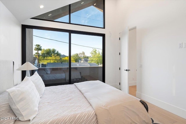 bedroom featuring high vaulted ceiling and wood-type flooring