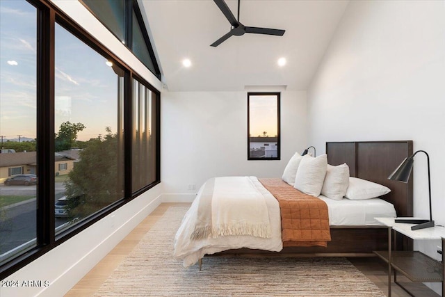 bedroom with multiple windows, light hardwood / wood-style floors, ceiling fan, and lofted ceiling