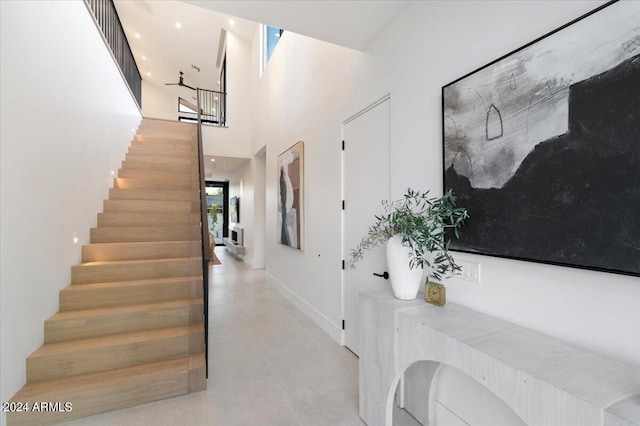 stairway with a towering ceiling and light tile floors