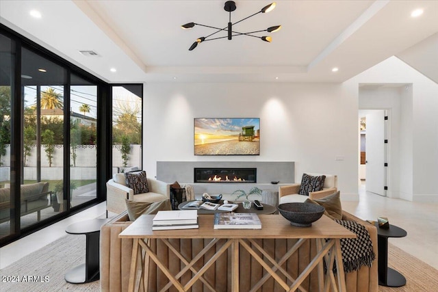 tiled living room with a notable chandelier, a wall of windows, and a raised ceiling