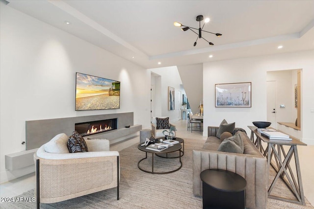 living room featuring a raised ceiling and an inviting chandelier