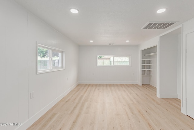 unfurnished room featuring a textured ceiling and light hardwood / wood-style flooring