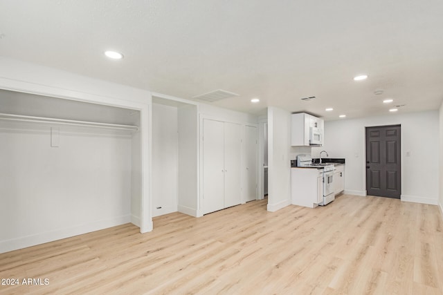 interior space featuring white cabinets, light wood-type flooring, white appliances, and sink