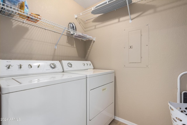 laundry area with laundry area, washing machine and dryer, electric panel, and baseboards