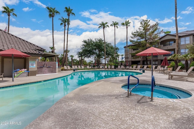 pool with a patio and a hot tub