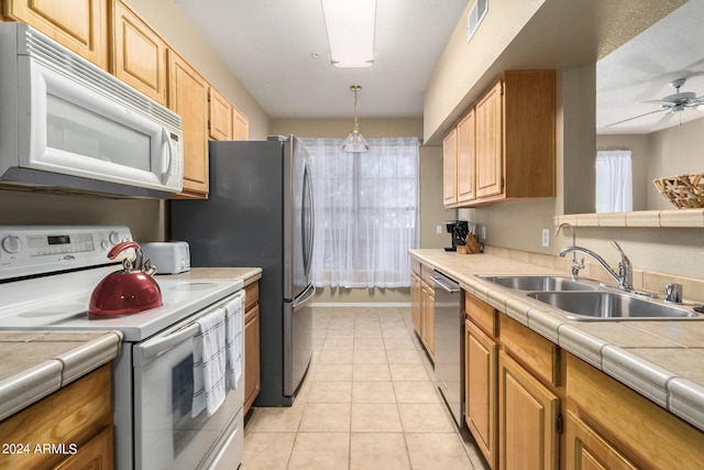 kitchen with light tile patterned floors, tile countertops, white appliances, a sink, and visible vents