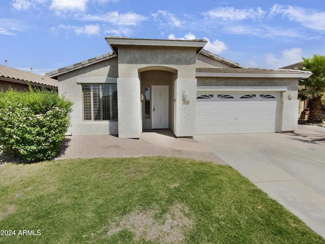 view of front of home featuring stucco siding, a front yard, a garage, and driveway