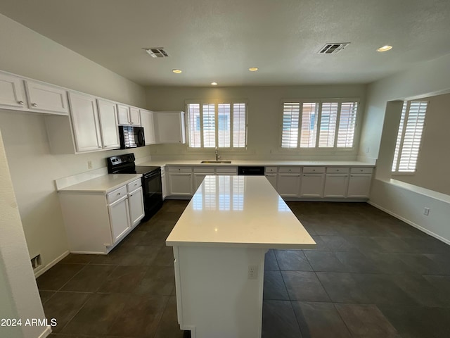 kitchen featuring white cabinetry, black appliances, visible vents, and a sink