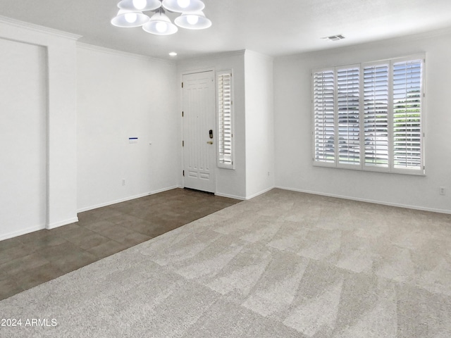 carpeted entrance foyer featuring a chandelier, visible vents, crown molding, and baseboards