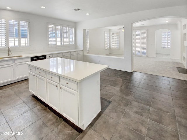 kitchen with visible vents, a kitchen island, a sink, carpet flooring, and open floor plan