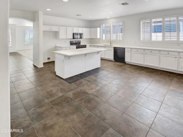 kitchen featuring visible vents, white cabinets, black appliances, and a sink