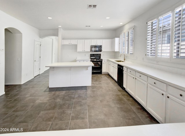 kitchen with visible vents, black appliances, a sink, arched walkways, and white cabinets