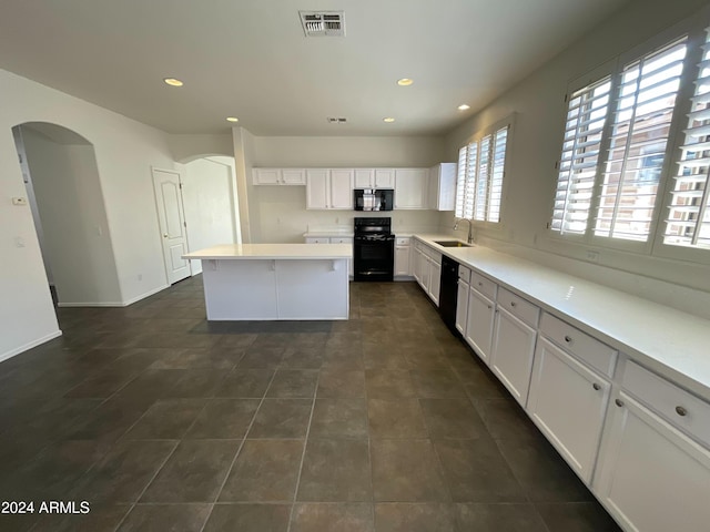 kitchen featuring black appliances, sink, dark tile patterned flooring, white cabinets, and a kitchen island