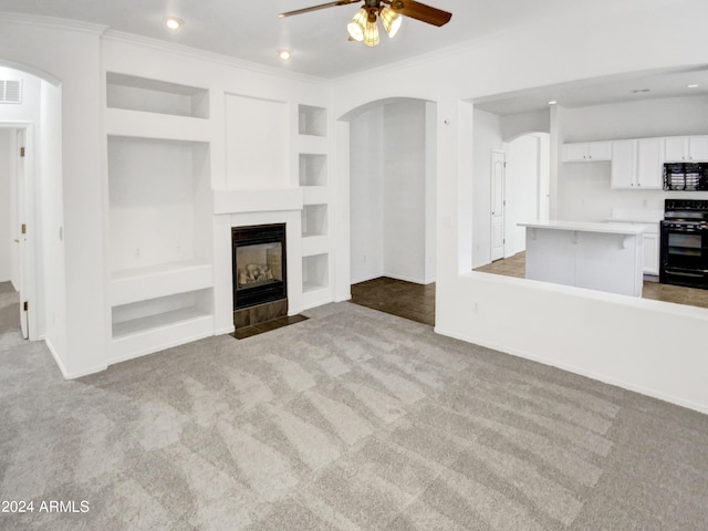 unfurnished living room with a fireplace, built in shelves, light colored carpet, and arched walkways