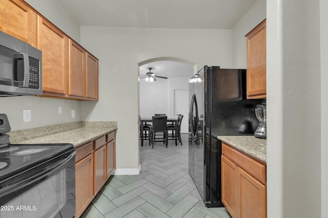 kitchen with arched walkways, brown cabinets, light countertops, a ceiling fan, and black appliances