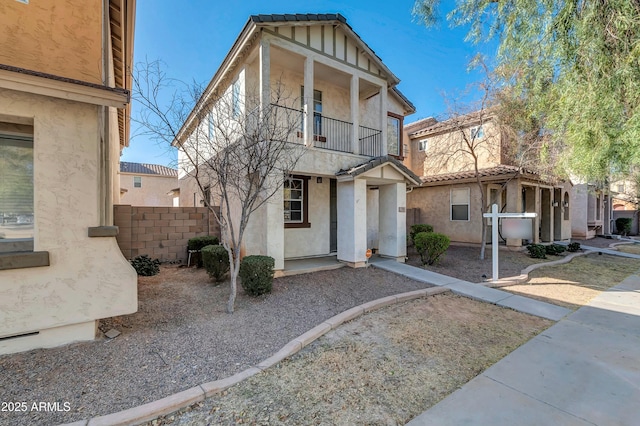 view of front of house featuring fence, a balcony, and stucco siding