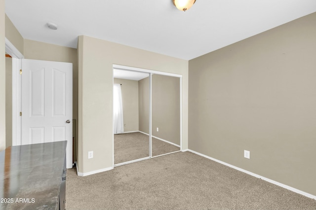 unfurnished bedroom with carpet floors, a closet, and baseboards