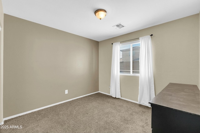 empty room featuring light colored carpet, visible vents, and baseboards