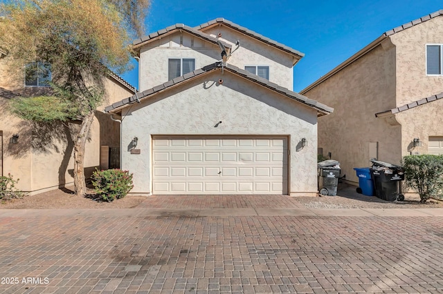 view of front of property featuring a garage, decorative driveway, and stucco siding