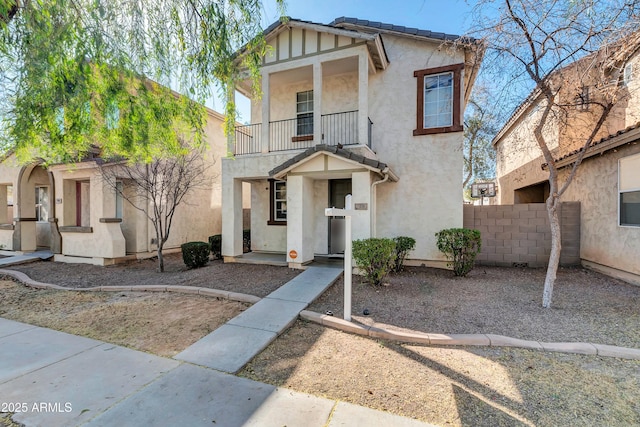 view of front of property with fence, a balcony, and stucco siding