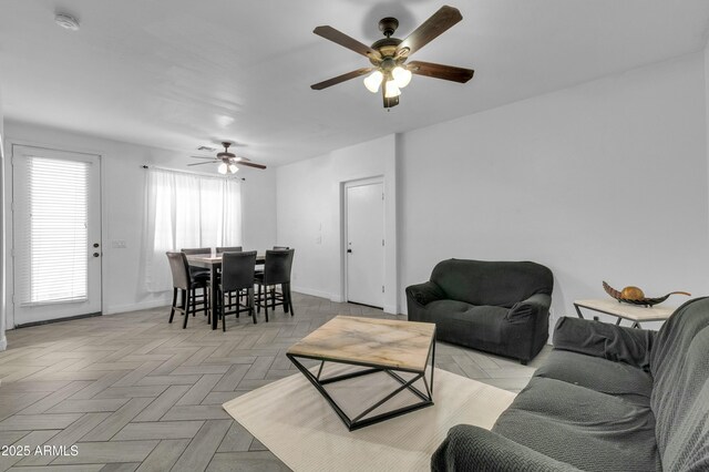 living area featuring baseboards and a ceiling fan