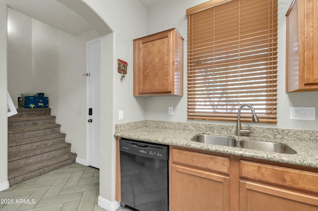 kitchen with black dishwasher, arched walkways, a sink, and light stone countertops