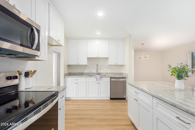 kitchen with stainless steel appliances, light hardwood / wood-style floors, white cabinets, sink, and decorative light fixtures