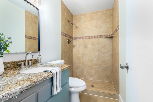 bathroom featuring vanity, toilet, and tiled shower