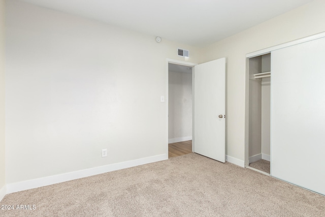 unfurnished bedroom featuring light carpet and a closet